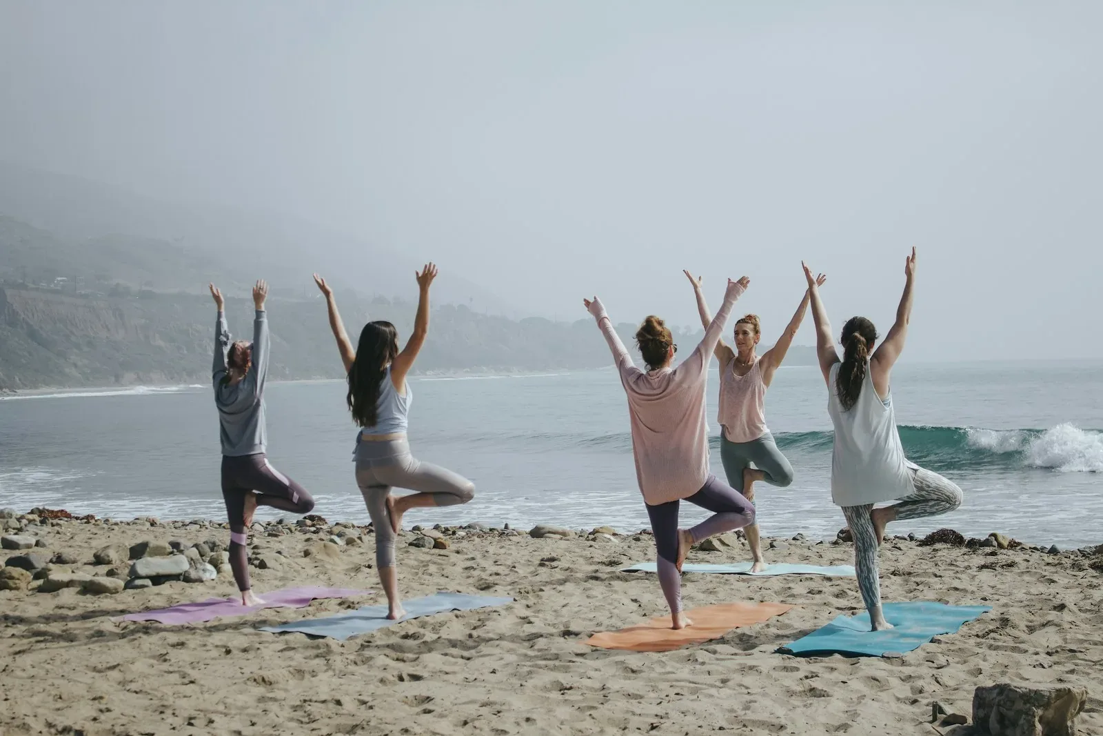 Person yn ymarfer yoga yn yr awyr agored